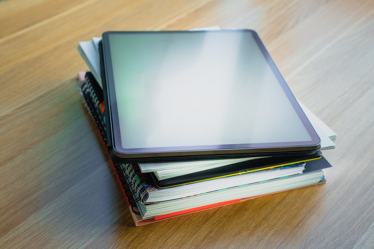 Digital tablet resting on top of a stack of books, depicting modern education and technology.